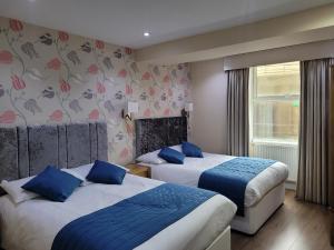 Cette chambre comprend 2 lits et une fenêtre. dans l'établissement George Hotel, à Londres