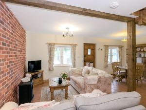 a living room with a couch and a brick wall at Drovers Cottage in East Meon