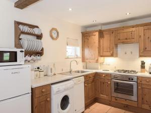 una cucina con armadi in legno, lavatrice e asciugatrice di Drovers Cottage a East Meon