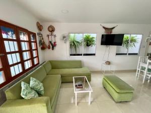 a living room with a green couch and a tv at Vivir La Costa - Casa de Fina in Ríohacha