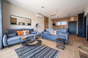 a living room with two blue couches and a table at Domki i apartamenty Skandynawia in Dąbki