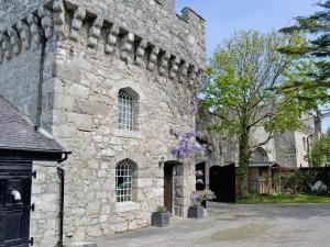 a stone building with purple flowers in front of it at Hen Wrych Hall Tower in Abergele