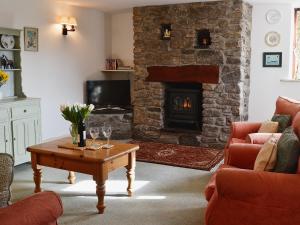 a living room with a fireplace and a table with wine glasses at Stable End in Trewen