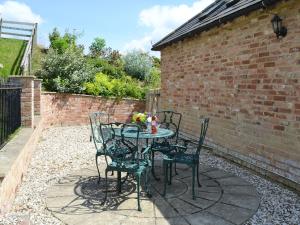 a patio with a table and chairs and a brick wall at The Apple House in Alderminster