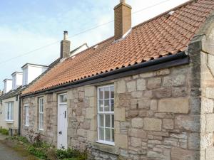 an old stone house with a red roof at West View Cottage in Seahouses