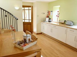 a kitchen with white cabinets and a wooden table at The Old Sunday School in Dalbeattie