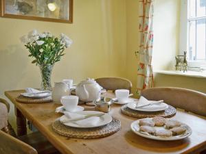 a wooden table with dishes and a vase of flowers at Sherrifs Lodge - Hw7730 in Myddfai