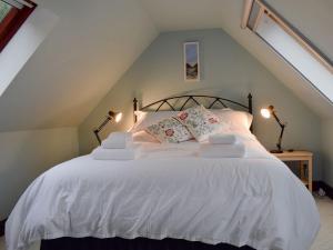 a bedroom with a white bed with two lamps at Drummond Cottage in Kenmore