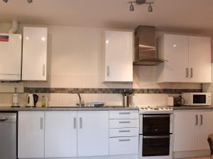 a white kitchen with white cabinets and appliances at Camelia Cottage in Witney