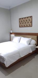 een groot bed met witte lakens en kussens bij Griya Sambilegi in Yogyakarta