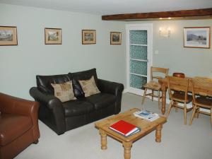 a living room with a leather couch and a table at Chapelfield Cottage in Rosthwaite