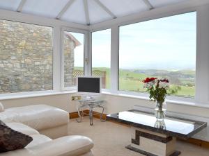 a living room with a couch and a table and windows at 4 Pengraig Draw in Llanychaiarn