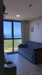 - un salon avec un canapé bleu et une grande fenêtre dans l'établissement Apartamento no 20º andar Barra Home Stay, à Récife