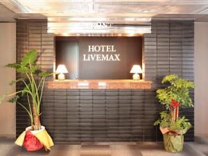 a hotel lobby with plants on a wall at HOTEL LiVEMAX BUDGET Chofu-Ekimae in Chofu