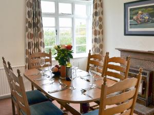 a dining room table with chairs and a large window at Windways in Port Erin