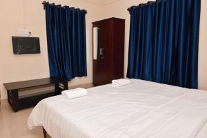 a bedroom with a large bed with blue curtains at VIP GARDEN RESORT in Varkala