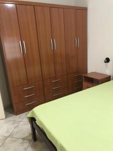 Habitación con armarios de madera y mesa verde. en Residencial Sombreiro en Florianópolis