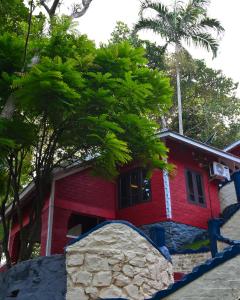 una casa roja con una roca delante de ella en VIP GARDEN RESORT, en Varkala