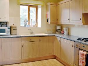 a kitchen with wooden cabinets and a sink and a window at Wykham in Nettleton