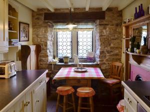 cocina con mesa con taburetes y ventana en Mullions Cottage, en Castleton