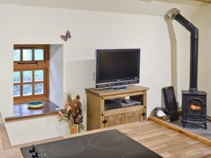 a living room with a tv and a wood stove at Yew Tree Bothy in Old Brampton