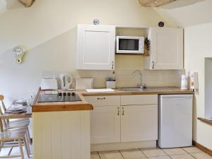 a kitchen with white cabinets and a sink and a microwave at Yew Tree Bothy in Old Brampton