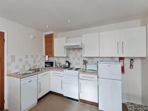 uma cozinha com electrodomésticos brancos e armários brancos em Pear Tree Farm Cottages - Rchm38 em Ebberston