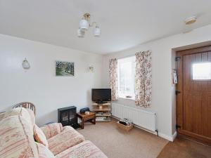 a living room with a couch and a television at Pear Tree Farm Cottages - Rchm38 in Ebberston