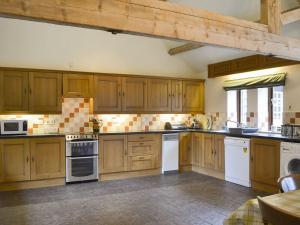 a large kitchen with wooden cabinets and white appliances at Skimblescott Barn in Monkhopton