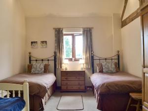 sypialnia z 2 łóżkami pojedynczymi i oknem w obiekcie Skimblescott Barn w mieście Monkhopton