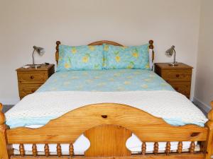 ein Schlafzimmer mit einem Holzbett mit zwei Nachttischen in der Unterkunft Glanmwrg Barn in Trostre