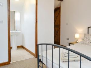 1 dormitorio con 1 cama y baño con lavamanos en Ysgubor, en Tregarth