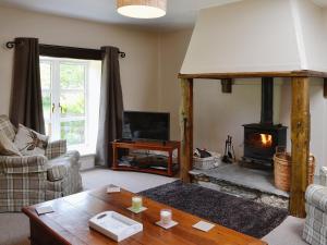a living room with a fireplace and a table at Woodside Cottage in Auchnastank