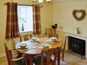 a dining room with a table and chairs and a fireplace at Woodside Cottage in Auchnastank