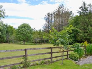 a wooden fence in front of a field at Woodside Cottage in Auchnastank