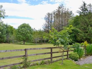 una valla de madera frente a un campo en Woodside Cottage en Auchnastank