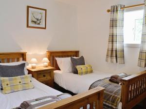 a bedroom with two beds and a window at Woodside Cottage in Auchnastank