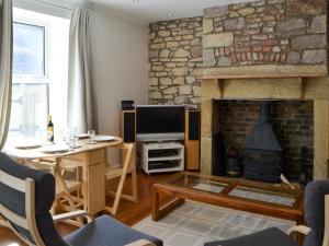 un soggiorno con camino, tavolo e TV di Oake Cottage a Warkworth