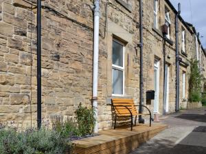 a bench sitting outside of a brick building at Oake Cottage in Warkworth