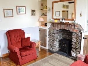 een woonkamer met een rode stoel en een open haard bij Sunrise in Looe
