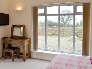 a bedroom with a window and a desk with a mirror at Haddocks Nook in Aldwark