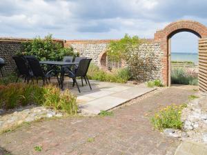 a patio with a table and chairs next to a brick wall at Smugglers Lookout in Mundesley