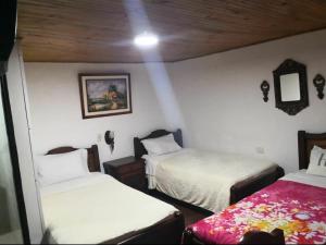 a bedroom with two beds and a wooden ceiling at Hotel Don Blas in Popayan