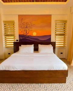 a bedroom with a bed with a painting on the wall at White Hut Villas by Asog resort in Naga