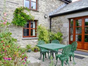 a green table and chairs in front of a building at Well Barn in Lanteglos