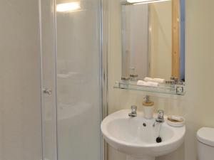La salle de bains blanche est pourvue d'un lavabo et d'une douche. dans l'établissement Cuil Lodge, à Kilmelfort
