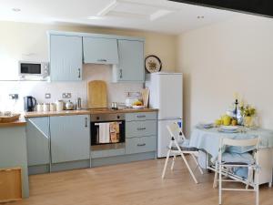 a kitchen with a table and a white refrigerator at Glendale Mews in Haltwhistle