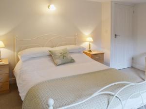 a bedroom with a large white bed with two night stands at Willow Cottage in Corpusty