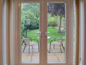 a sliding glass door with two chairs and a table at Willow Cottage in Corpusty