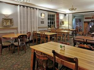a dining room with wooden tables and chairs at Blue Charm in Damerham